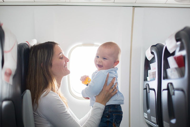 Mum and baby smiling on a plane ready to go on holiday.