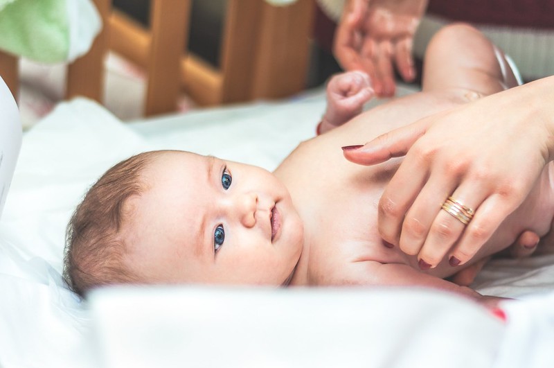 Newborn baby boy gazing up at his mum while she changes his nappy.