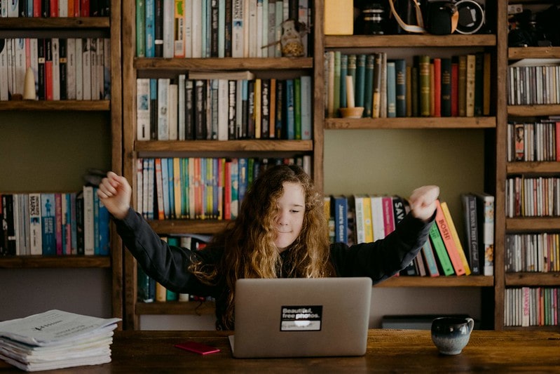 Girl studying at desk with her laptop, happy that she has understood her work.