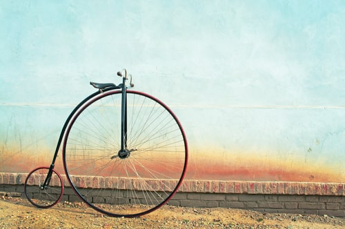 Penny farthing stationary next to a wall.