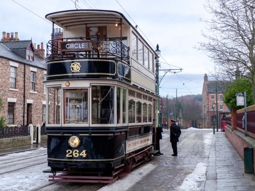 Victorian double-decker tram stopping to allow passengers on.