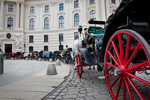 Victorian horse drawn stagecoaches in front of a grand building.