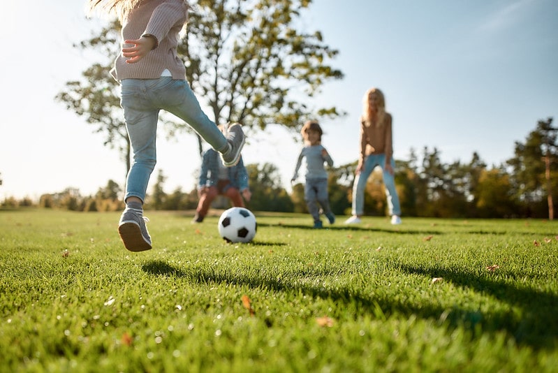 Kids passing a football to each other playing happily outdoors.