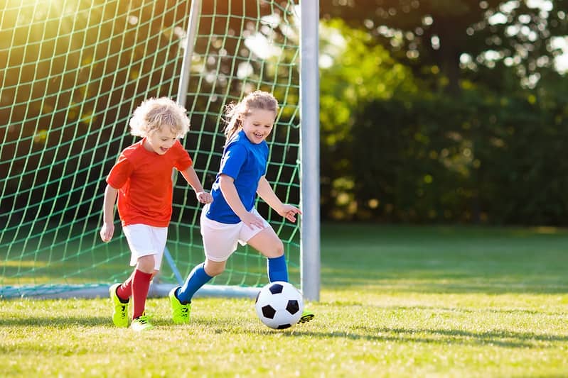 To barn i hagen nyter en runde fotball.