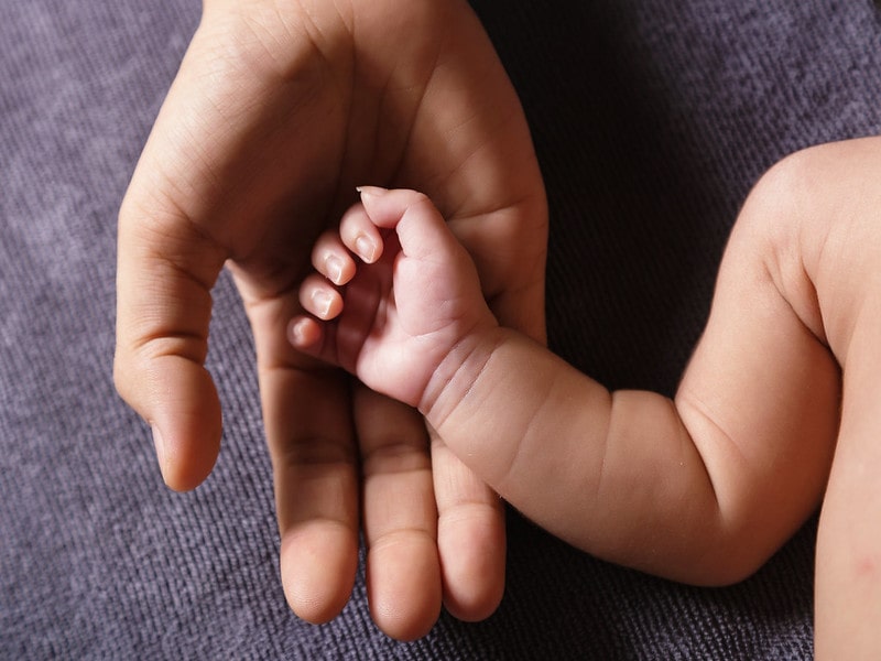 Small baby's arm in its parent's hand.