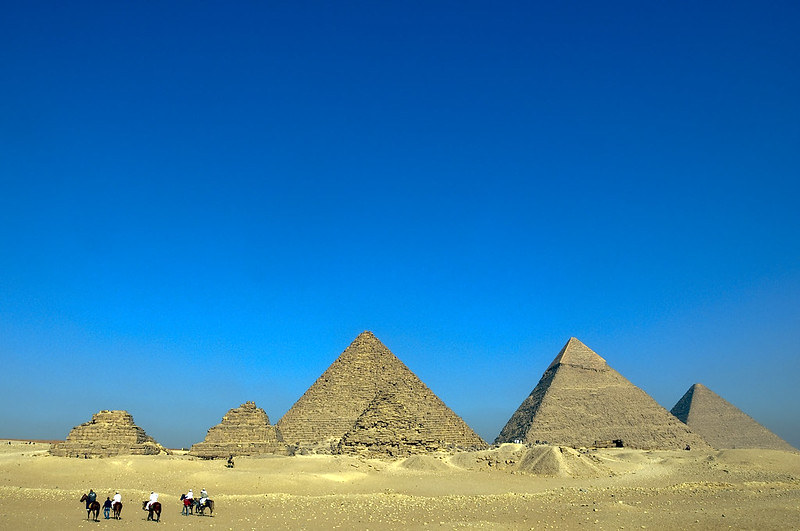 A desert with six pyramids in the centre, against a vivid blue sky on a sunny day.