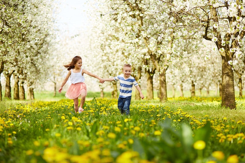 A boy and girl running through Swanley Park holding hands