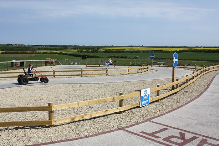 Kids karting around a track on pedal go-karts.