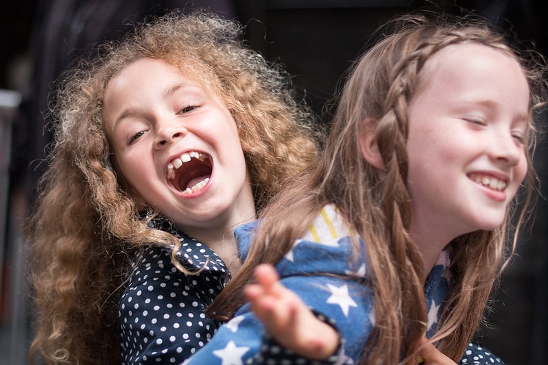 Two young girls smiling and joking around.
