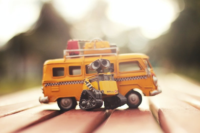 Yellow Wall-E robot toy next to a yellow school bus toy.