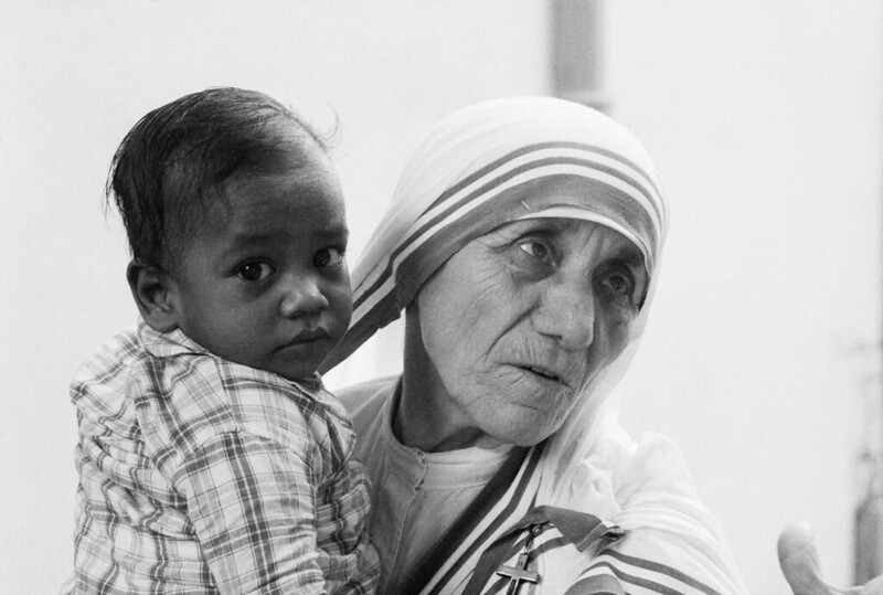 Mother Teresa holding a young boy in her arms.