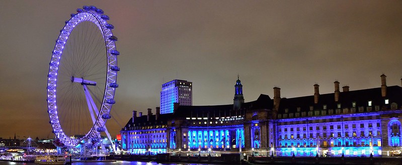 A view from Westminster Bridge of the London Eye lit up at night.