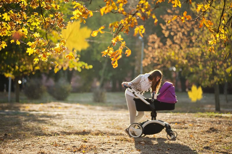 Mum looking at her baby in the stroller on a walk in the park.