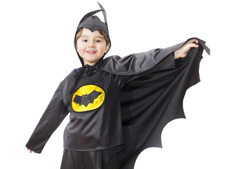 Young boy wearing a batman costume smiling.