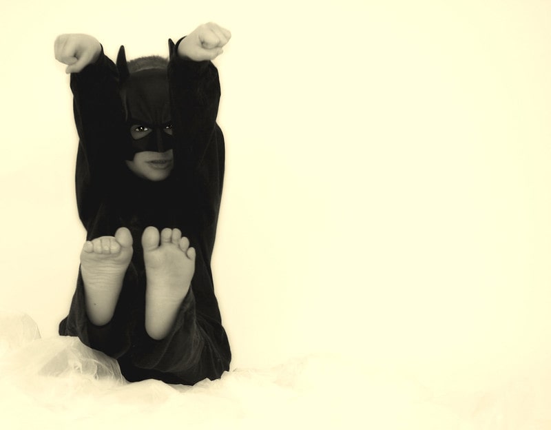 Young boy wearing batman costume pretending to fight the enemies.