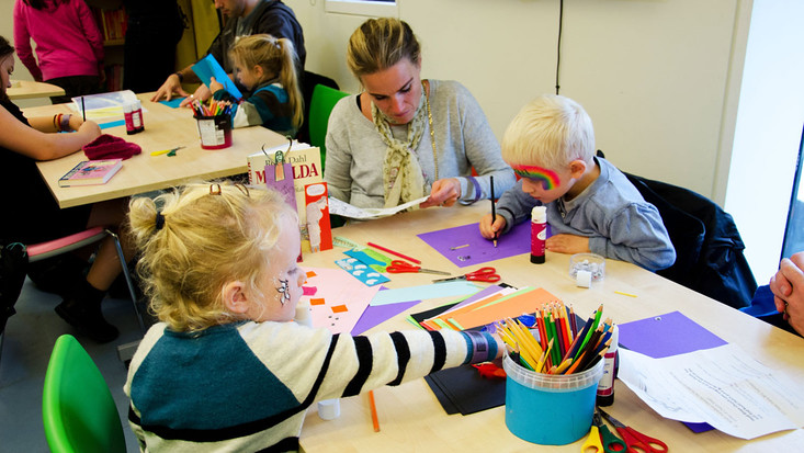 parents and children doing arts and crafts together at the free entertainment service kids table