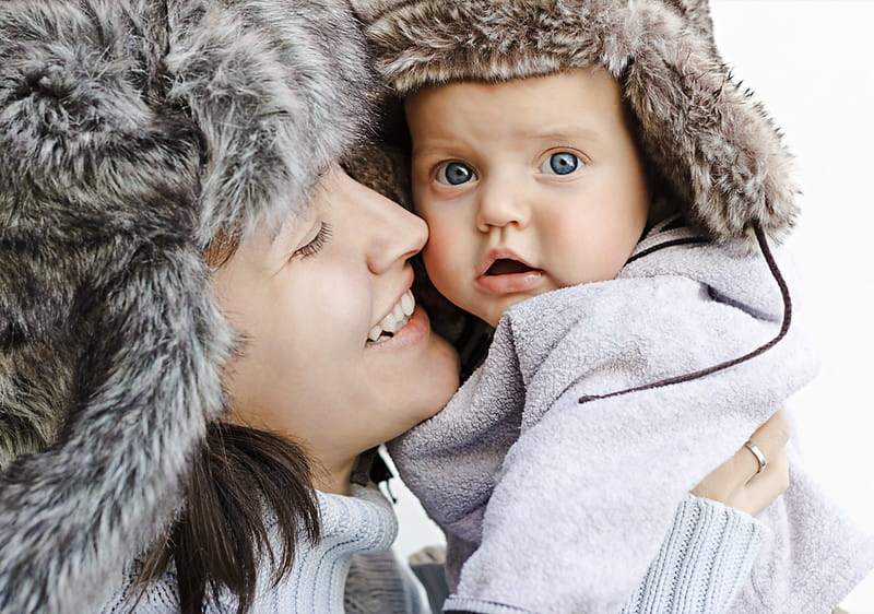 Mum and baby both wearing faux fur winter hats.