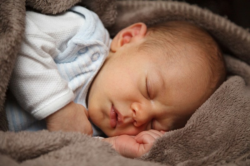 Baby sleeping in a brown blanket.