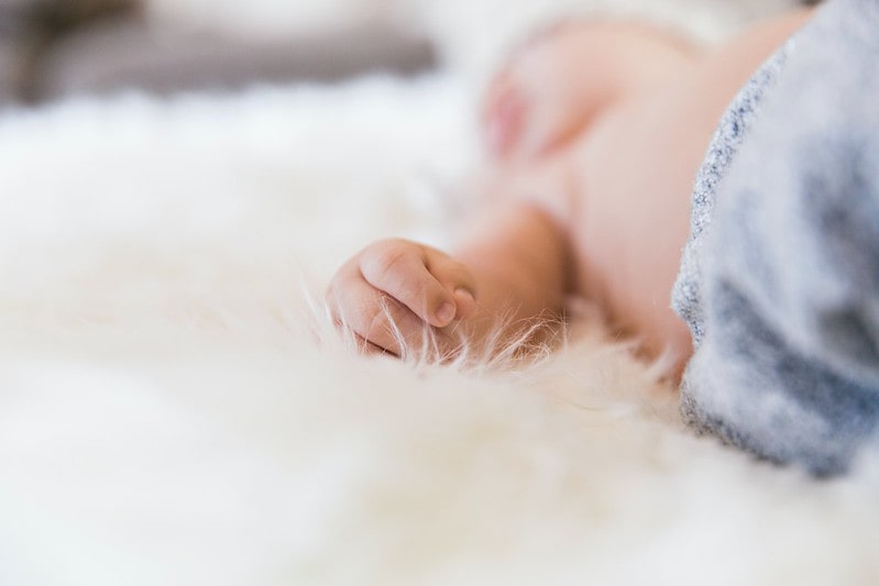 Baby sleeping on a white fluffy blanket.