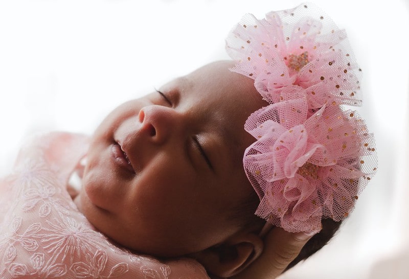 Sleeping baby girl wearing a pink net flower headband.