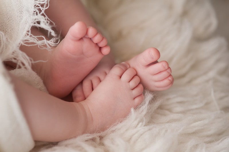 Two pairs of baby feet poking out the blanket.