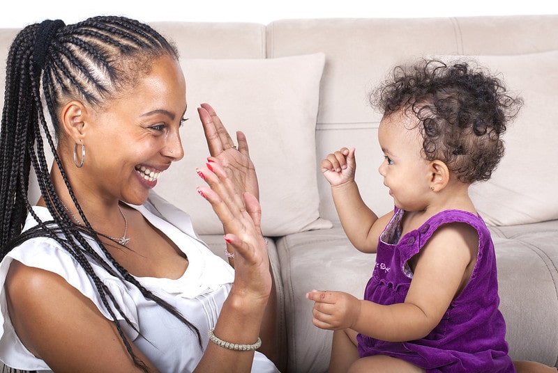 Mum and her baby daughter playing and smiling at each other.