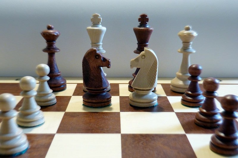 Wooden chess set with the pieces all lined up.