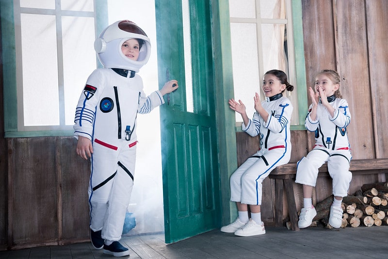 Three kids in astronaut costumes happy and enjoying themselves.