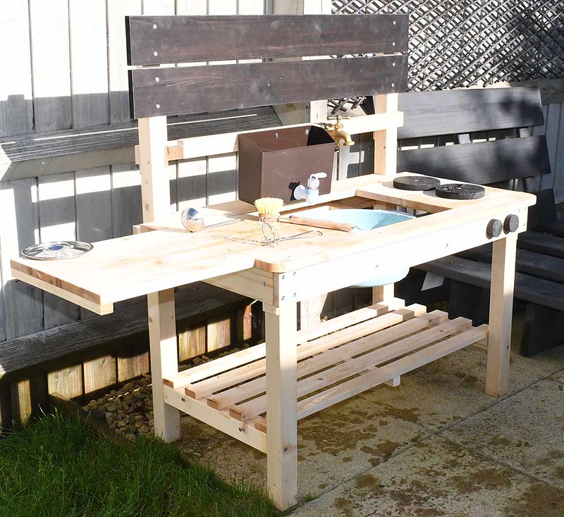 A Big Game Hunters Mud Kitchen outside, with tap, chalkboard, hobs and water dispenser.