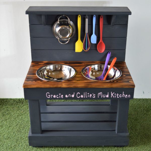 A Mini Mud Kitchens Pebble Two Bowl with mixing bowl, opening oven, 4 hob rings, movable knobs, parcel shelf and utensils.