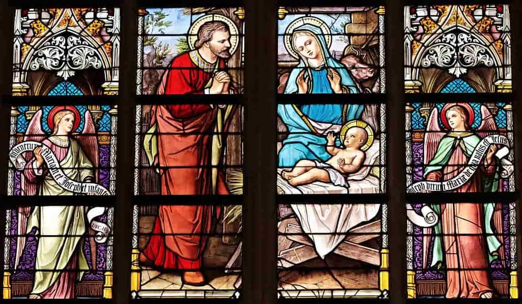 Stained glass church window depicting a colourful scene of the baby Jesus.