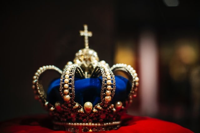 Blue crown bejewelled with pearls and gold, resting on a velvet cushion.