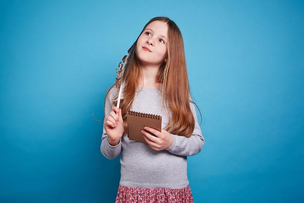 Little girl holding a pen and paper thinking about Anglo-Saxon England.