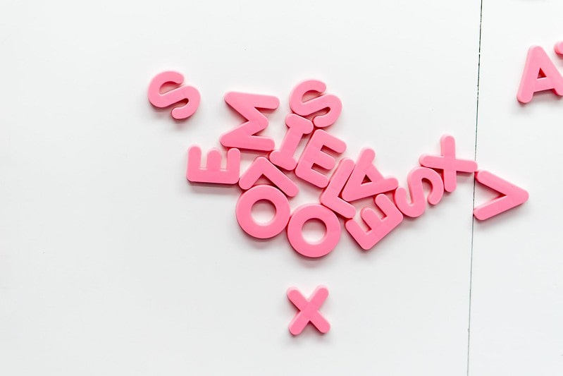 Pink letter magnets stuck to the fridge using magnetic force.