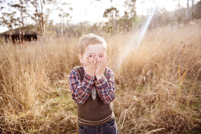 Boy in a field standing and laughing at Shrek jokes.