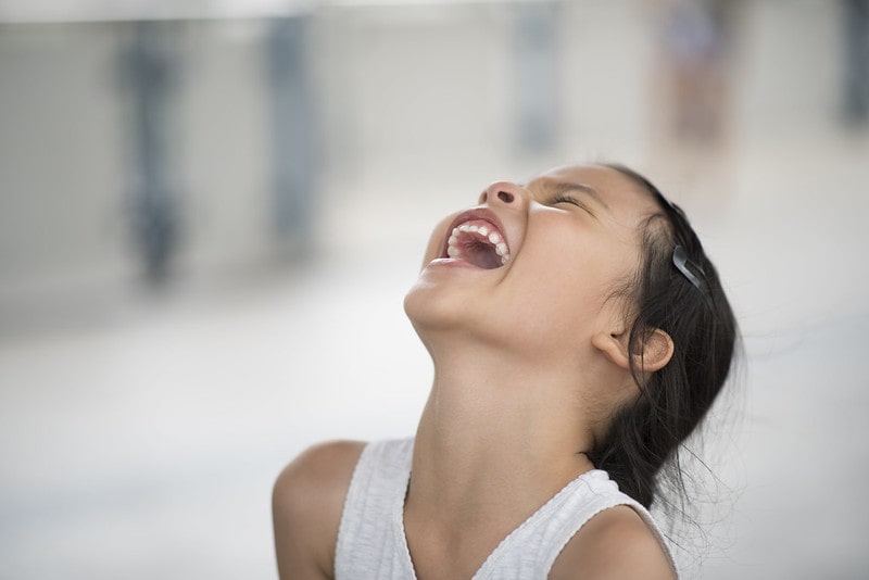 Girl throwing her head back in laughter at Shrek jokes.