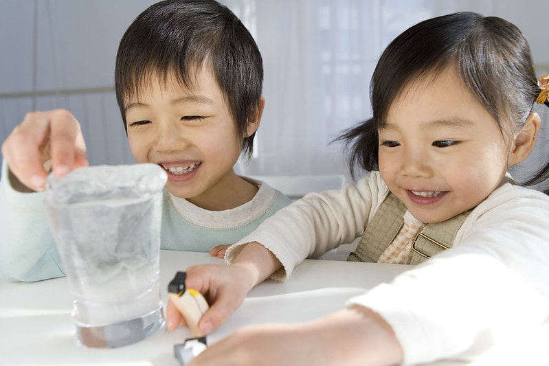 Brother and sister playing with toy penguins and ice.