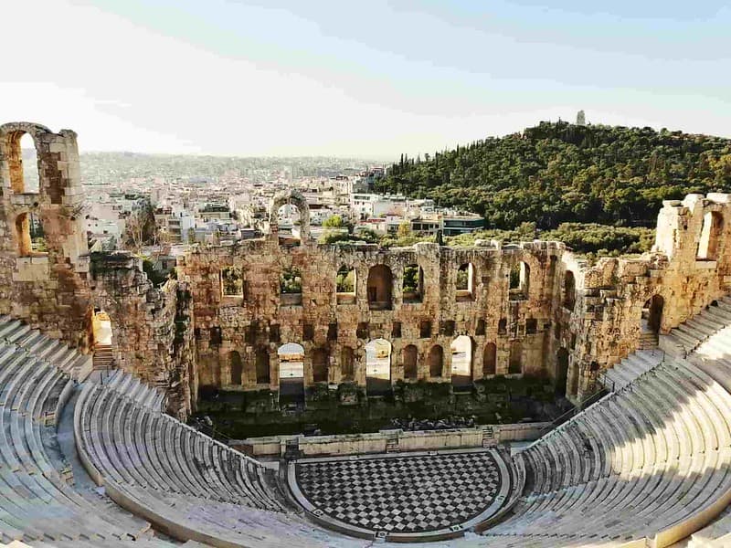 Ancient Greek amphitheatre with a view over the city and a hill.