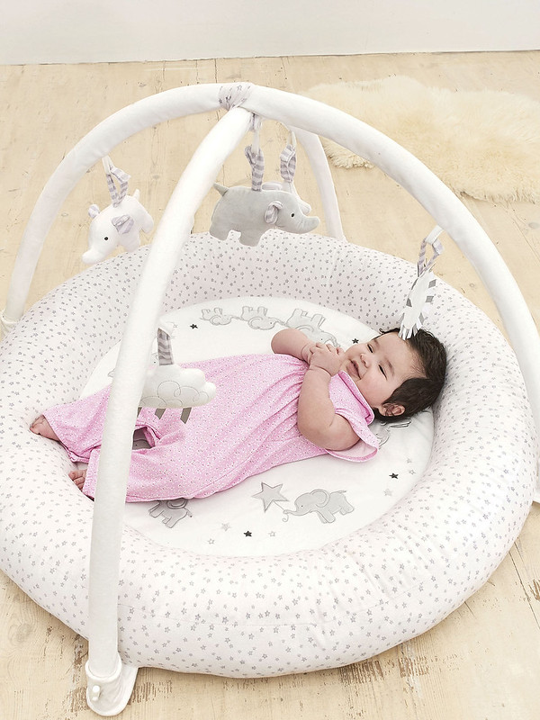 A baby playing with an Elephant Activity Baby Gym and Playmat.