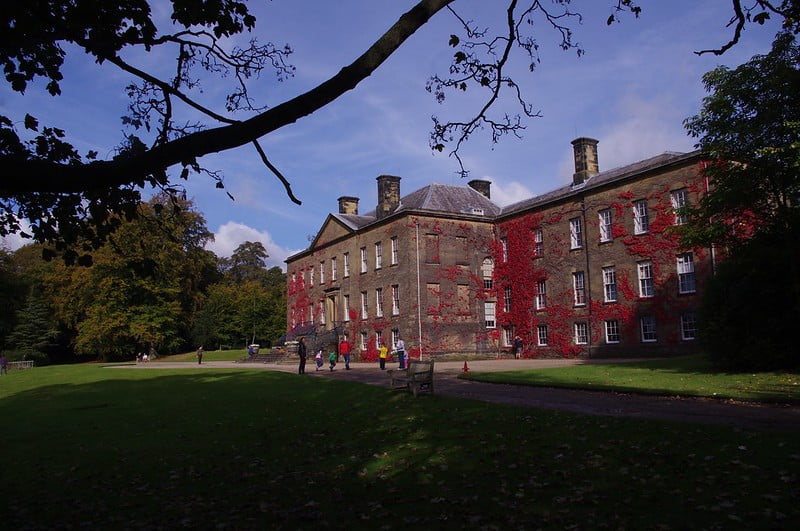 The historic Erddig House with surrounding trees and visitors admiring the facade.