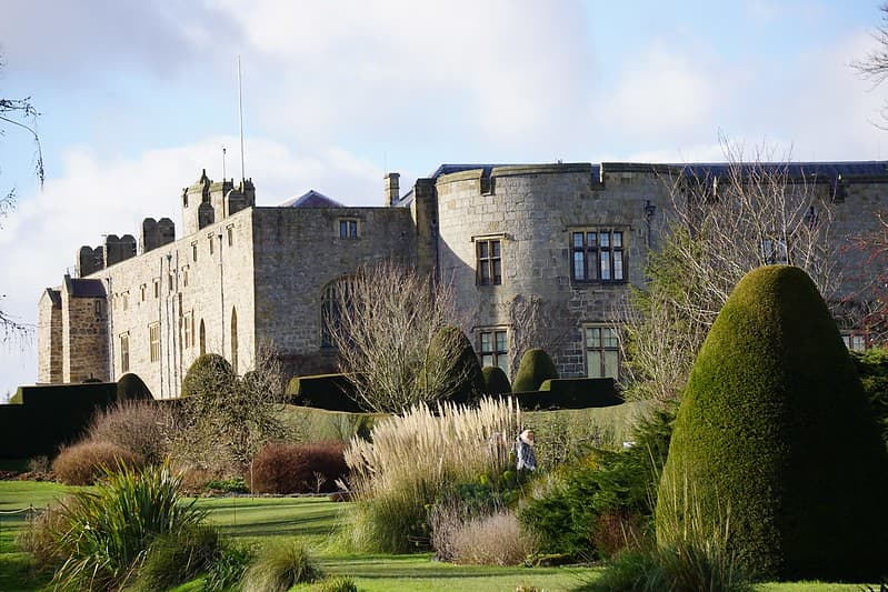 View of Chirk Castle from the gardens with a variety of green plants and hedges.