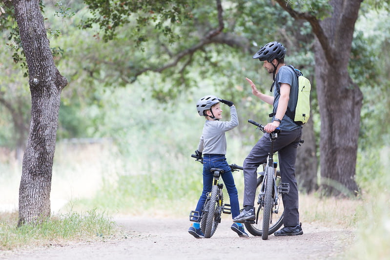 Dad and son giving each other a high five as they've finished a long cycle.