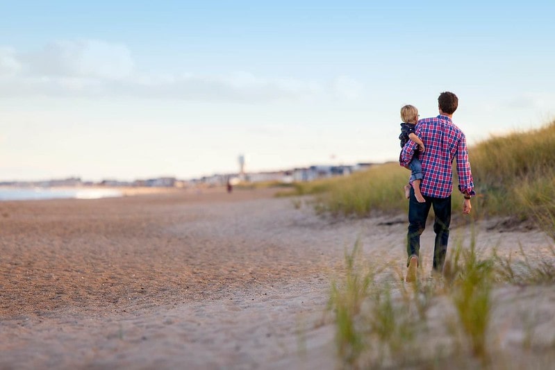 Dad carrying his young son in his arms as he walks along he beach in Hull.