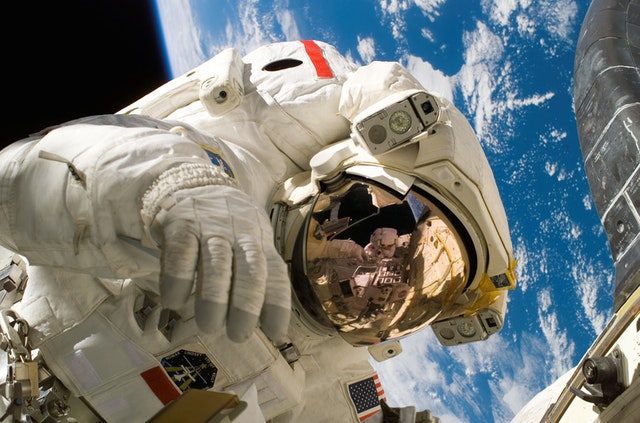 An astronaut in outer space with the Earth in view behind them.