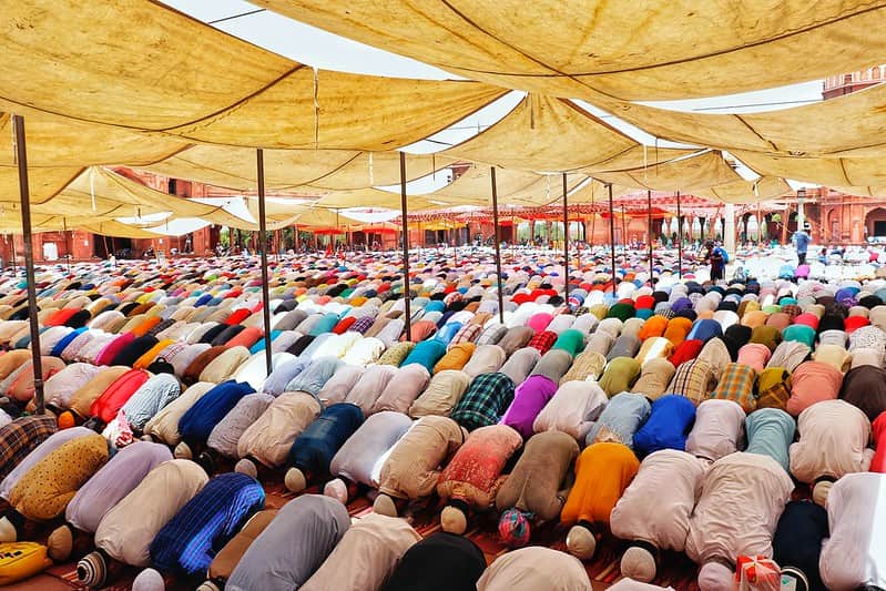 Rows of men bent over, bowing their heads in prayer at the mosque.