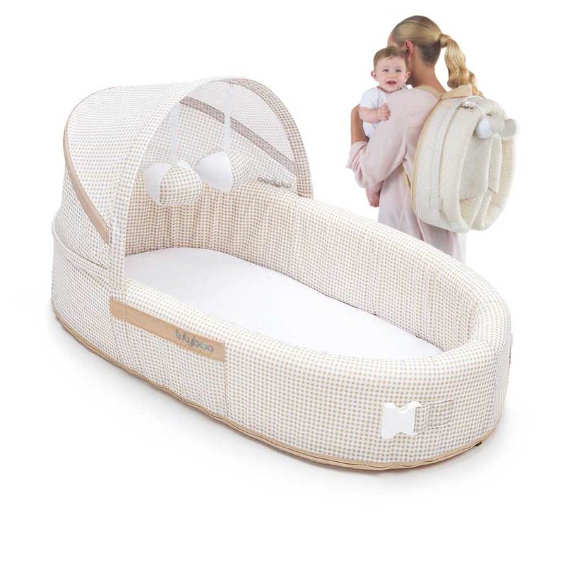 Mum carrying the baby and the Lulyboo Baby Lounge To Go Travel Bed.