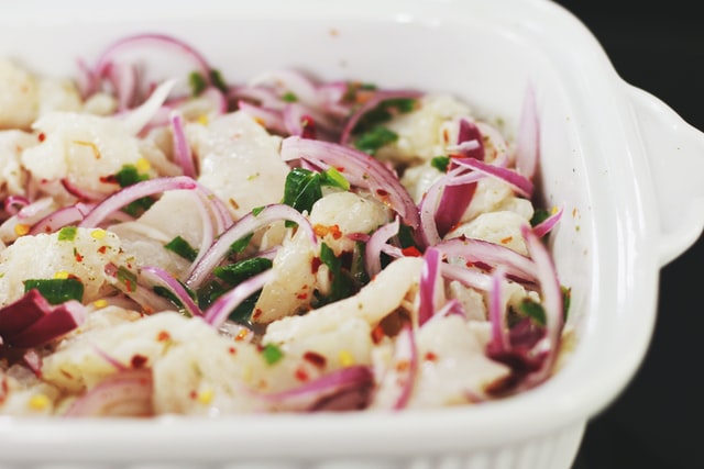 Dish of white fish ceviche with red onions and chilli flakes.
