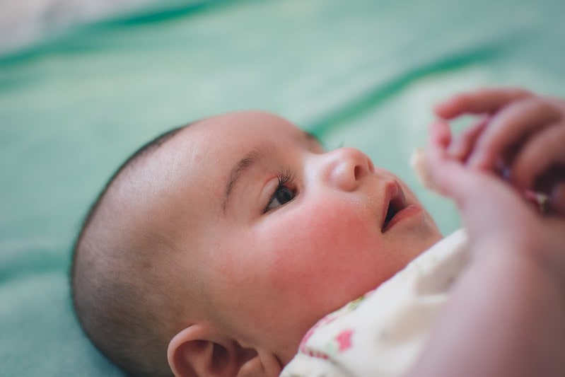 Newborn baby lying on its back gazing at its mother.