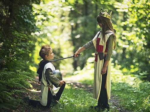 Kids playing dress up and pretending to be knights out in the garden.
