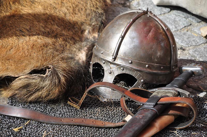 A mediaeval helmet, sword and armour lying on the stone floor.